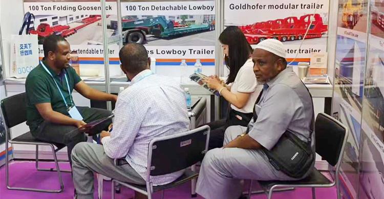 Clientes nigerianos visitan el stand de TITAN en la Feria de Cantón para comprar un remolque de cuello de cisne plegable.